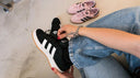 Person wearing adidas Campus 00s Black White Gum shoes with pink pairs in the background on a casual setting.