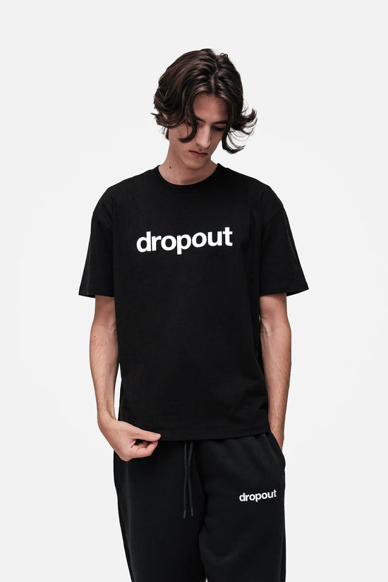 Person wearing a black 'dropout' t-shirt and pants on a white background