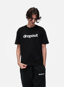 Person wearing a black 'dropout' t-shirt and pants on a white background