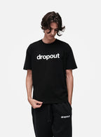 Person wearing a black 'dropout' t-shirt and pants on a white background