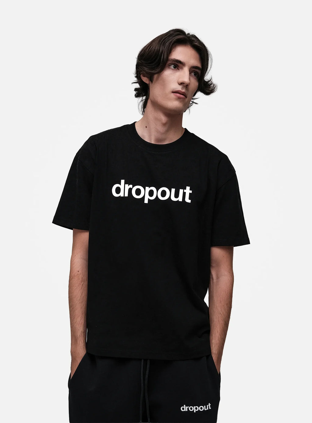 Person wearing a black 'dropout' t-shirt on a white background