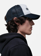 Person wearing a black and White/Navy cap with 'drkshdw' branding on a light gray background