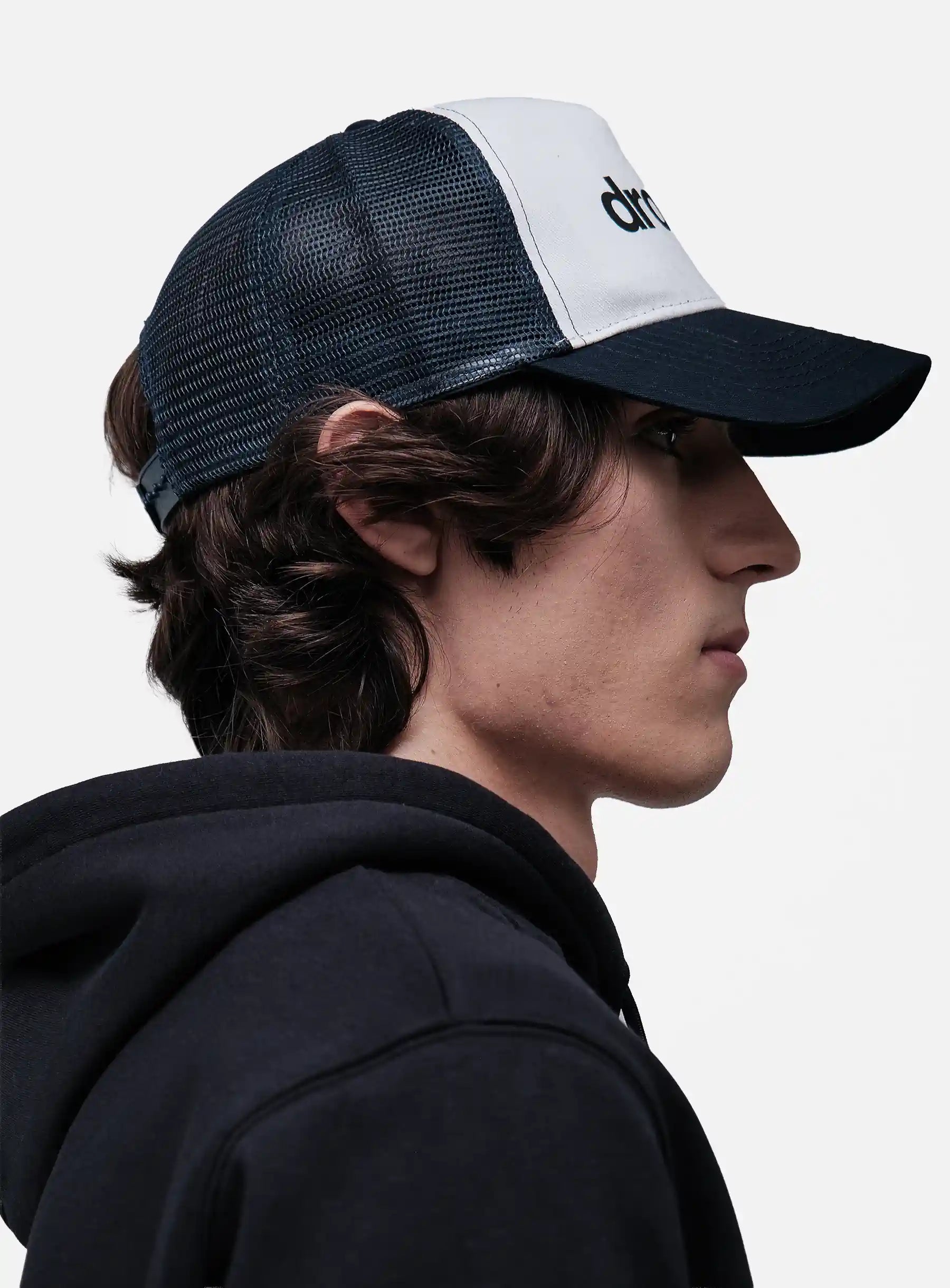 Person wearing a black and White/Navy cap with 'drkshdw' branding on a light gray background