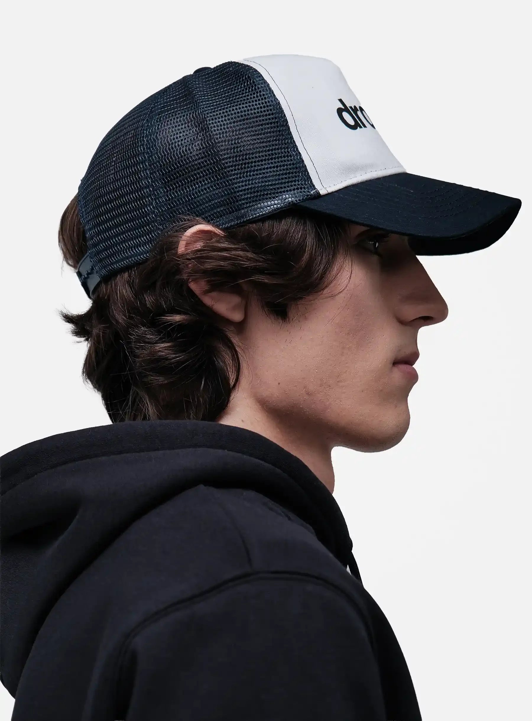 Person wearing a black and White/Navy cap with 'drkshdw' branding on a light gray background