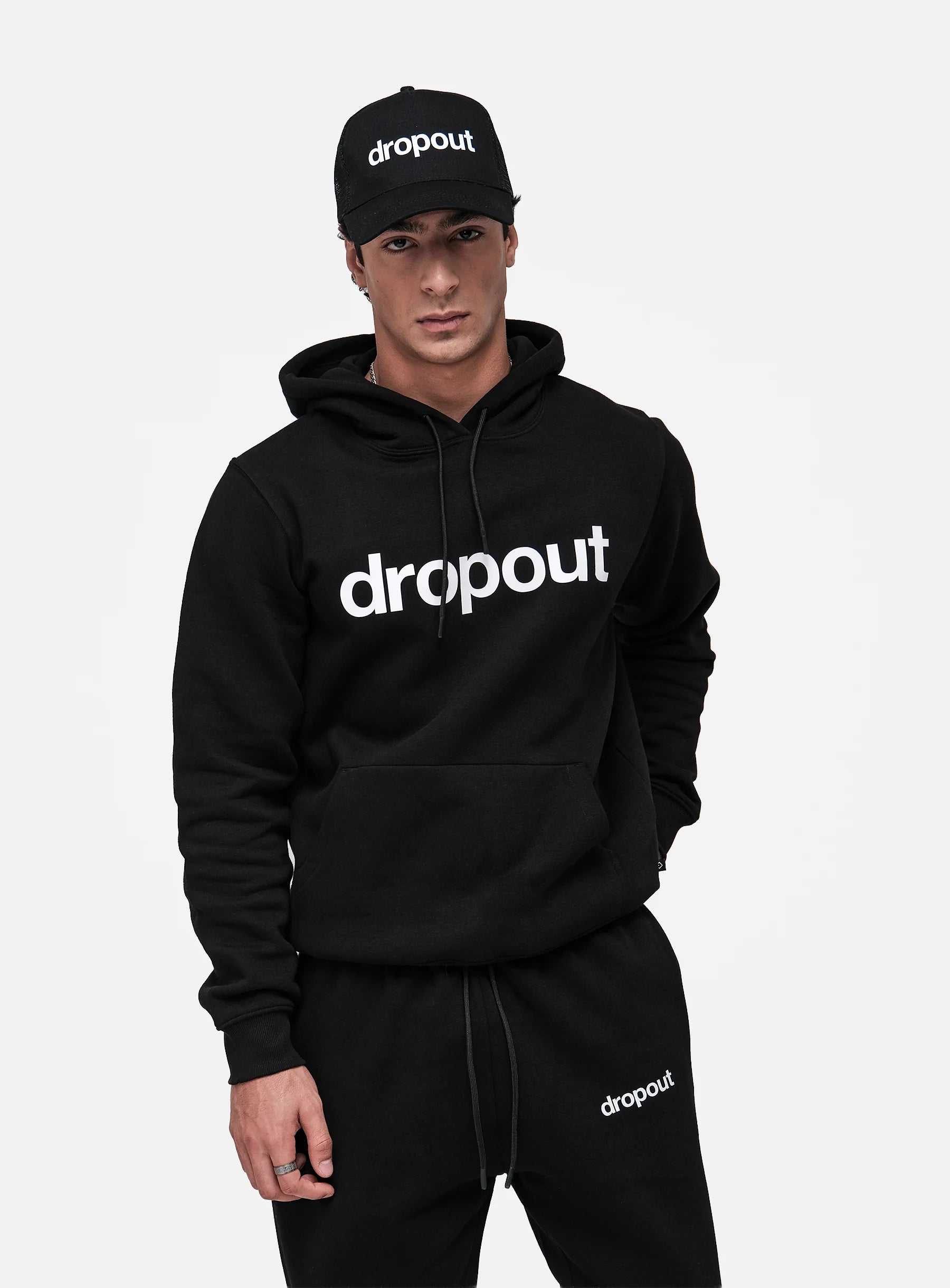 Person wearing a black 'dropout' hoodie and cap on a white background