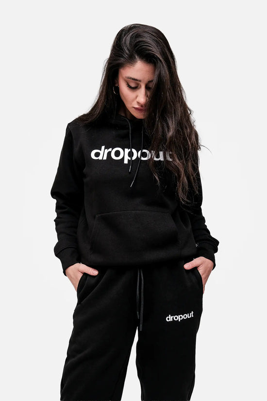 Person wearing a black hoodie and pants with 'dropout' logo on a white background