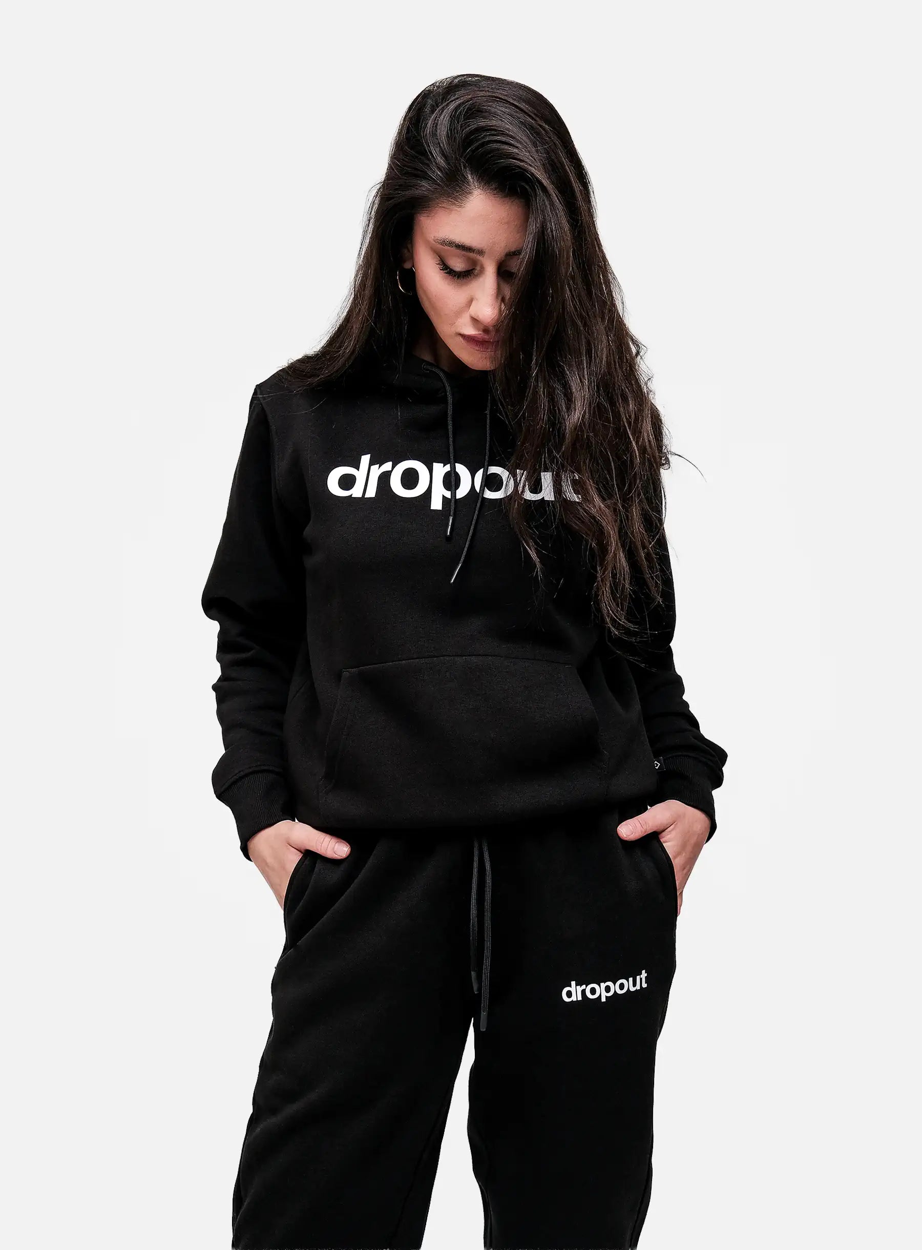 Person wearing a black hoodie and pants with 'dropout' logo on a white background