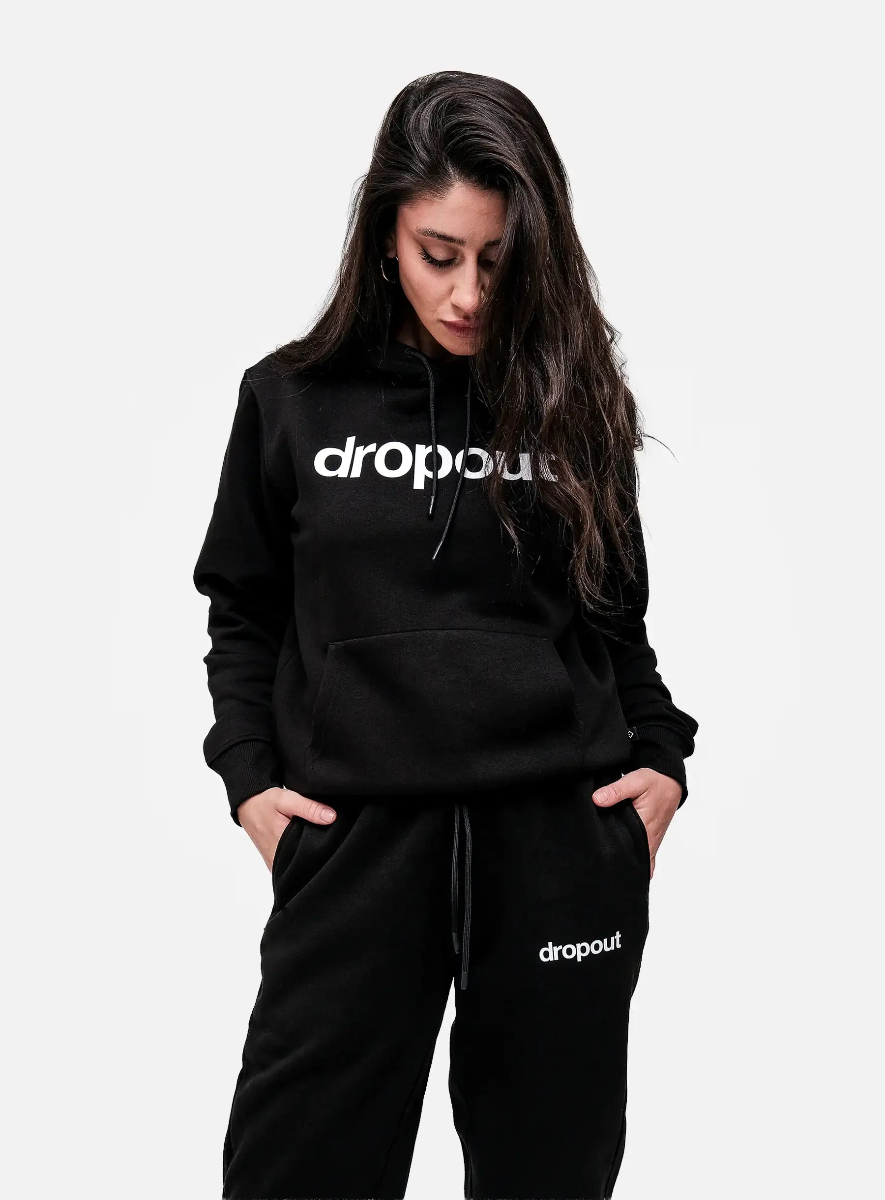 Person wearing a black hoodie and pants with 'dropout' logo on a white background