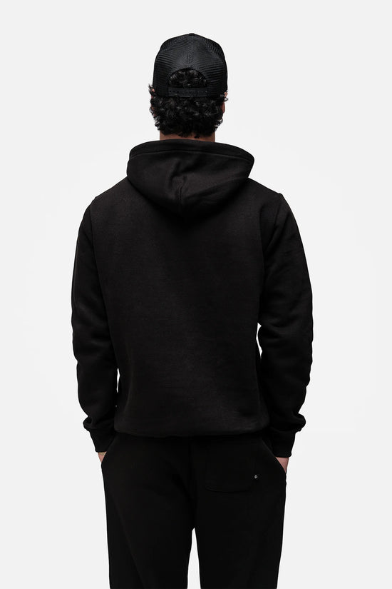 Person wearing a black hoodie and pants on a white background