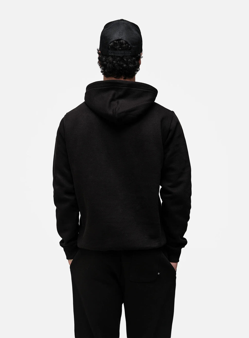 Person wearing a black hoodie and pants on a white background