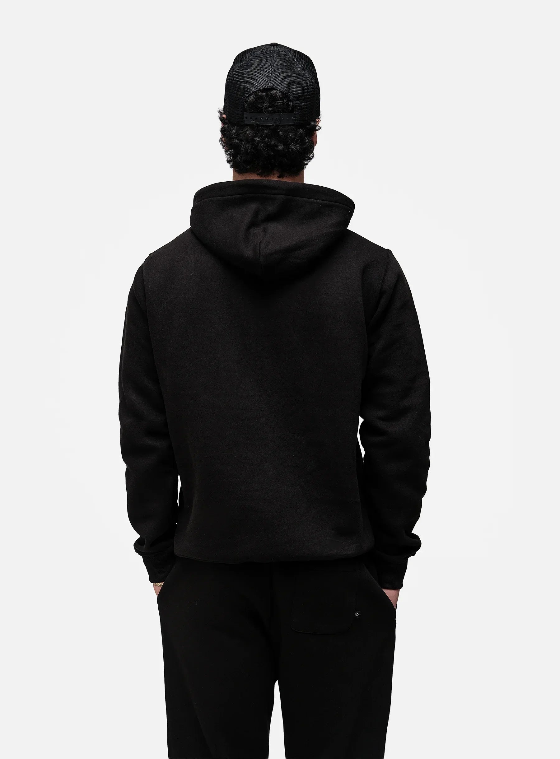 Person wearing a black hoodie and pants on a white background