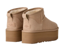 Pair of beige UGG boots with platform sole on a light gray background