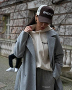 Person wearing a Beige hoodie, jacket, and Brown/Beige cap with 'dropout' branding in an urban setting.