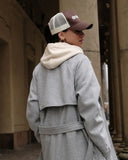 Person wearing a gray coat and a Brown/Beige cap with 'dropout' logo, standing outdoors.