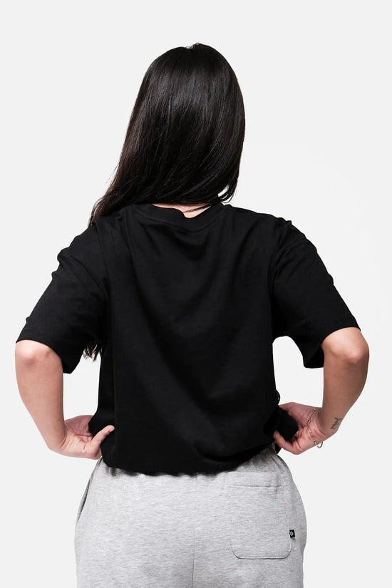 Person wearing a black oversized t-shirt and gray pants on a white background