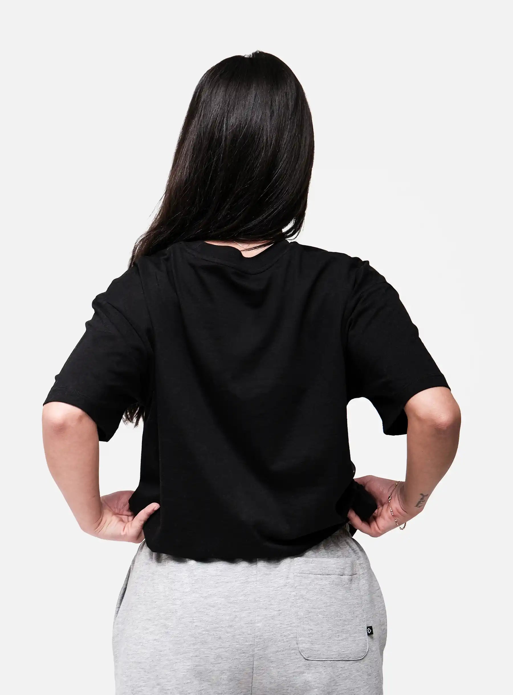 Person wearing a black oversized t-shirt and gray pants on a white background