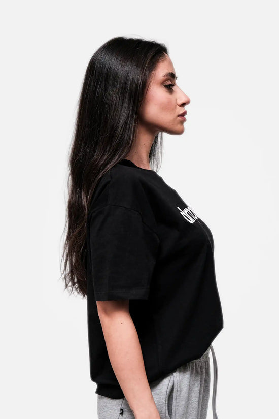 Woman wearing a black oversized t-shirt with a logo on a white background