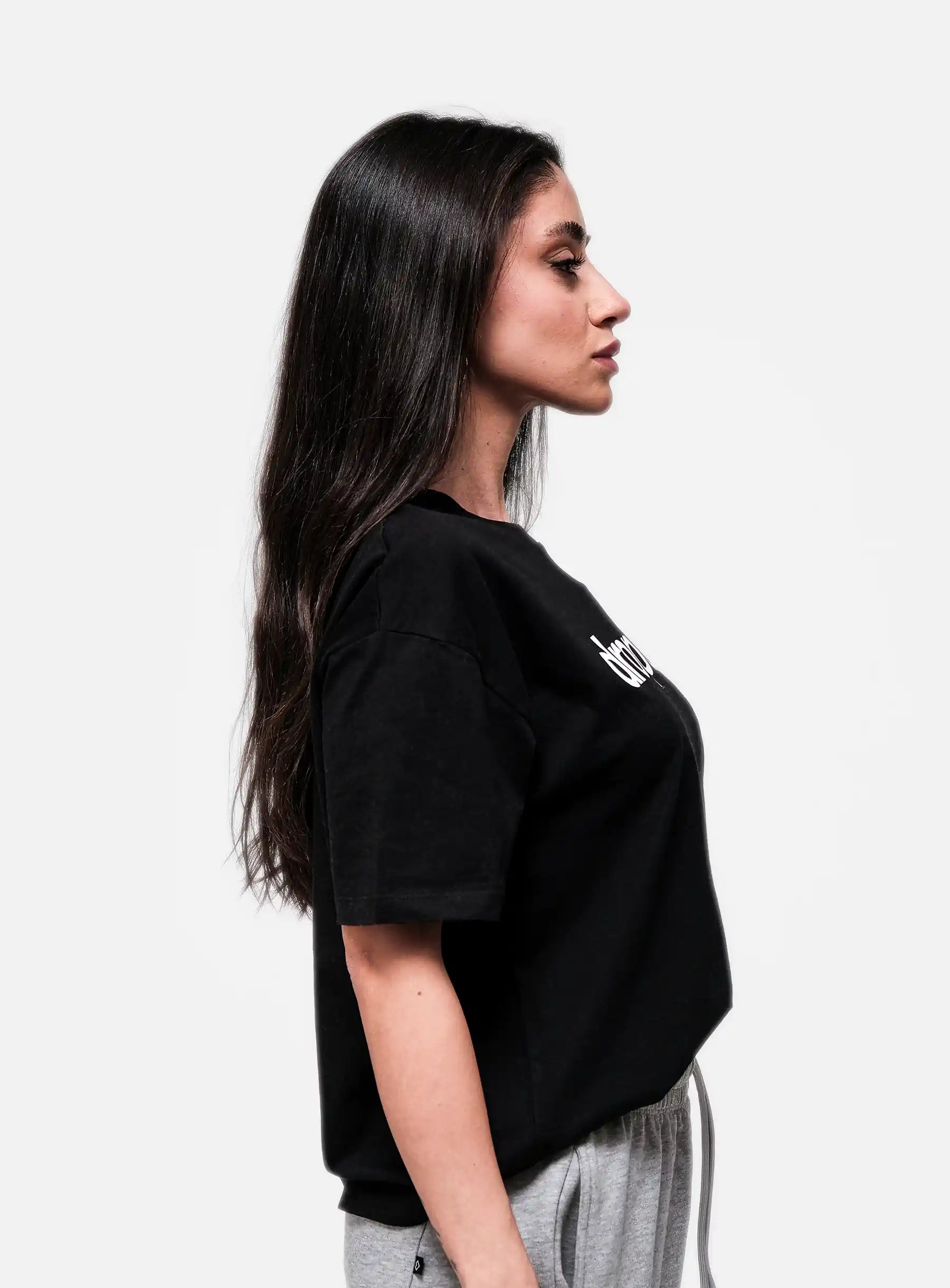Woman wearing a black oversized t-shirt with a logo on a white background