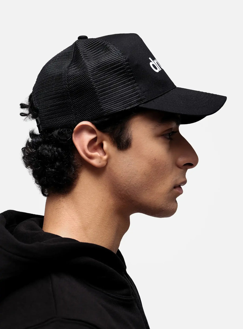 Side view of model in black dropout Milano trucker hat and hoodie, streetwear style