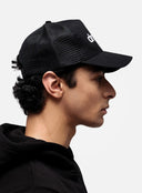Side view of model in black dropout Milano trucker hat and hoodie, streetwear style