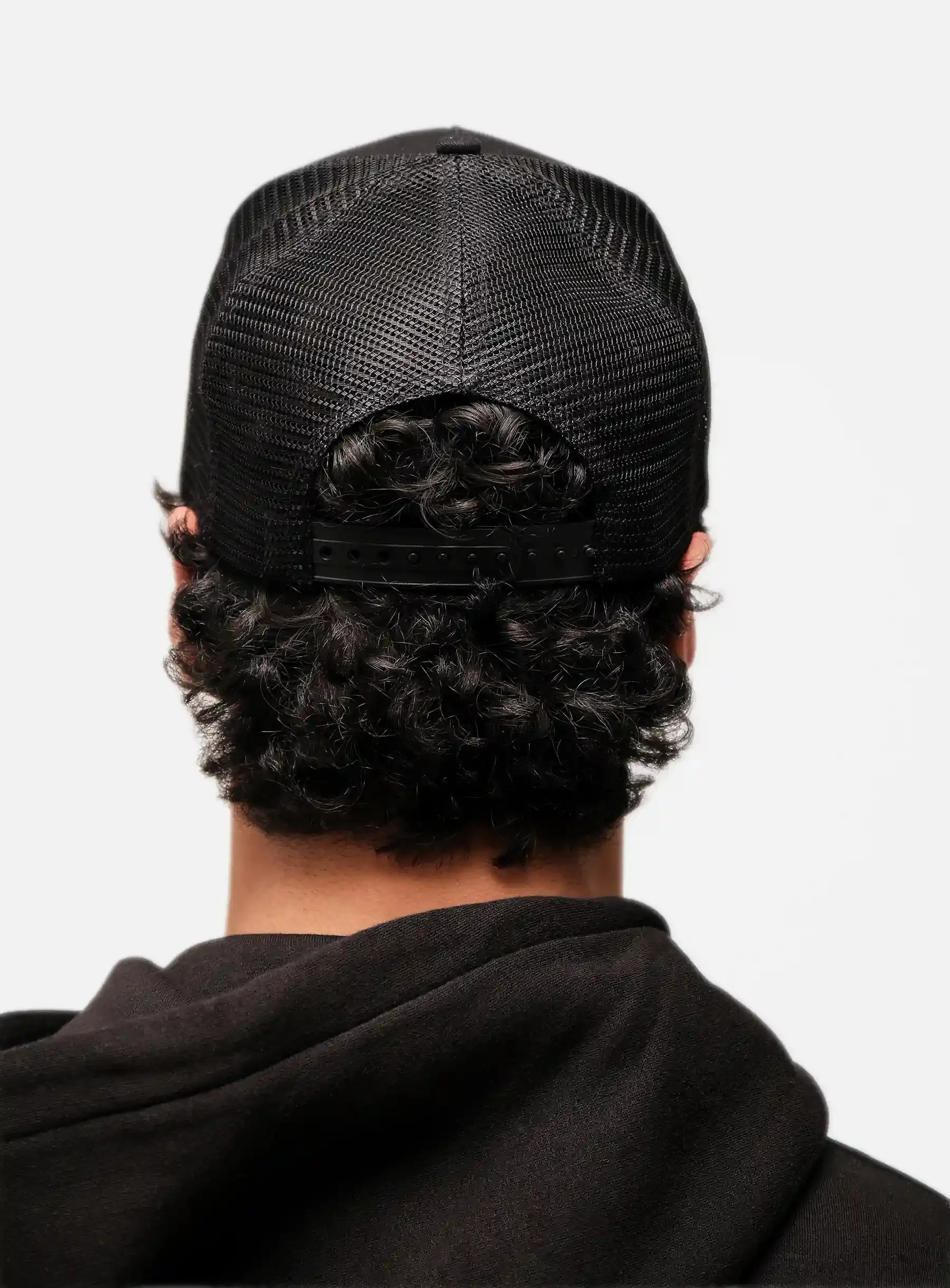 Back view of a person wearing a black mesh trucker hat and black hoodie, dropout streetwear