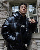 Person wearing a black puffer jacket with a brand logo, standing outdoors.