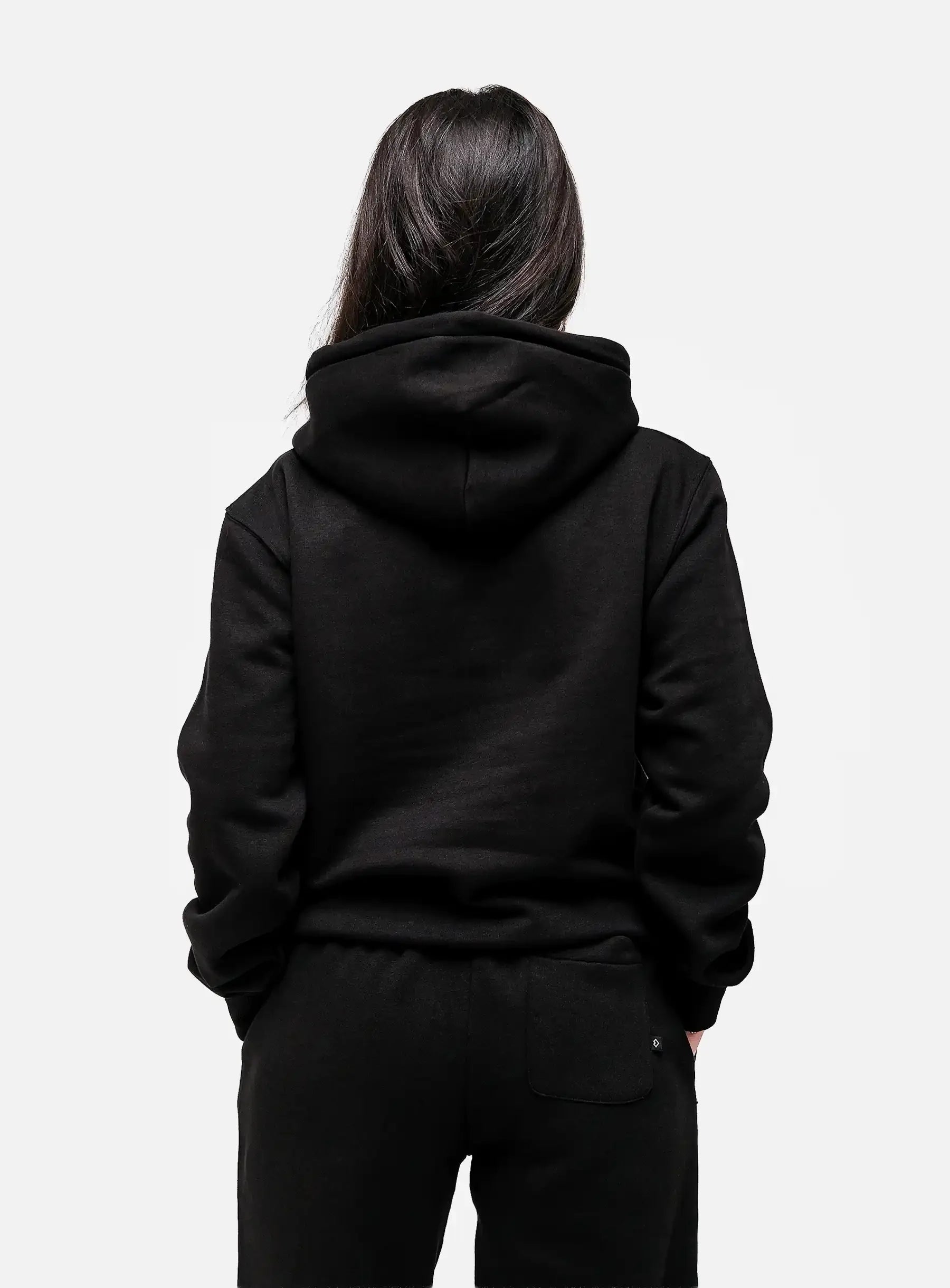 Person wearing black hoodie and sweatpants, back view, streetwear fashion