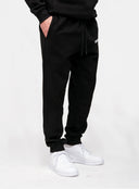 Black streetwear sweatpants with drawstring waist and white sneakers on model