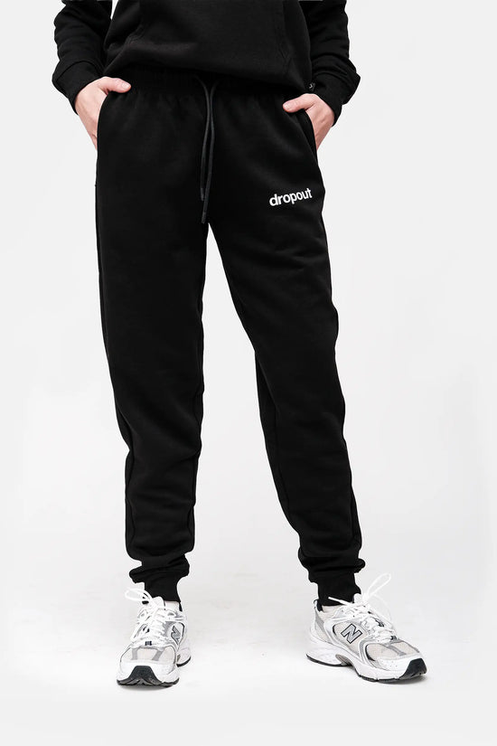 Person wearing black 'dropout' sweatpants on a white background