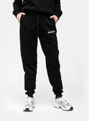 Person wearing black 'dropout' sweatpants on a white background