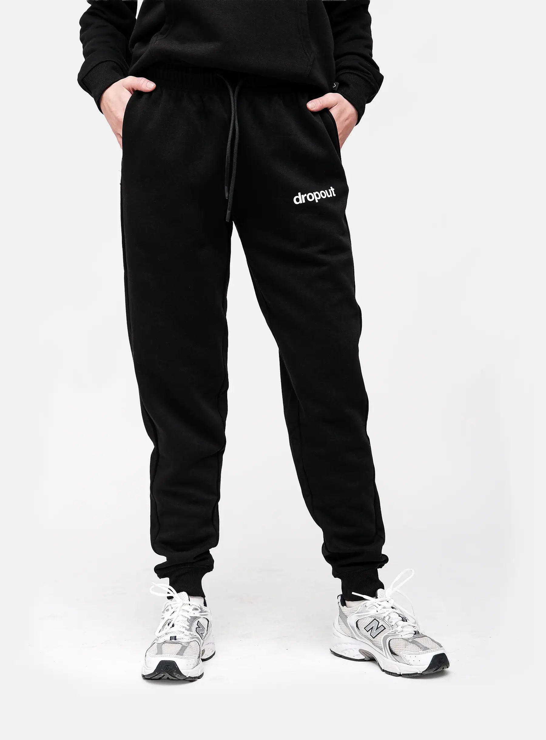 Person wearing black 'dropout' sweatpants on a white background