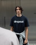 Person wearing a navy t-shirt with 'dropout' text against a gray background