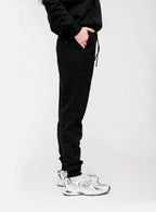 Person wearing black sweatpants and white sneakers on a white background