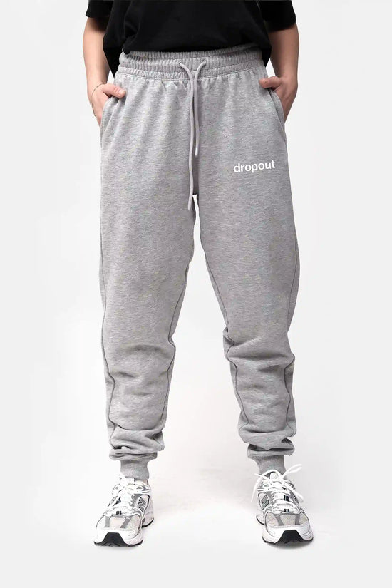 Person wearing grey sweatpants with 'dropout' logo on a white background