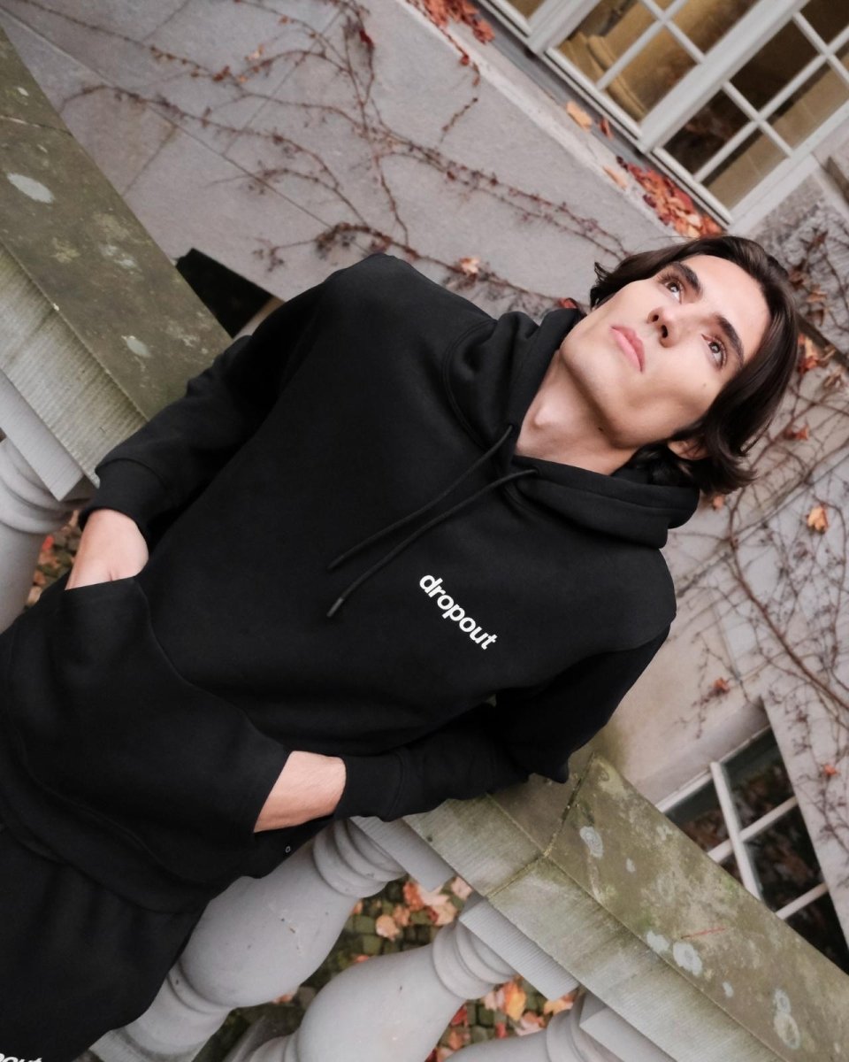 Person wearing a black hoodie with 'dropout' text, standing outdoors.