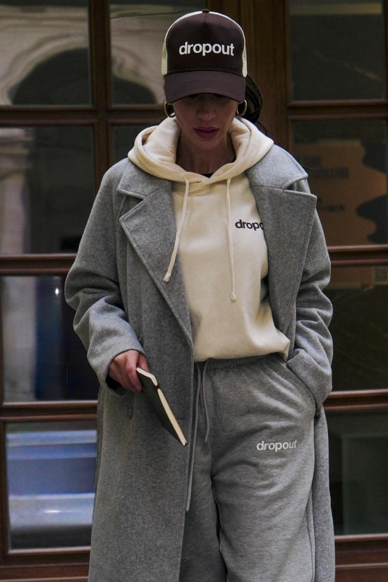 Person wearing a Beige hoodie, and gray pants with 'dropout' branding.