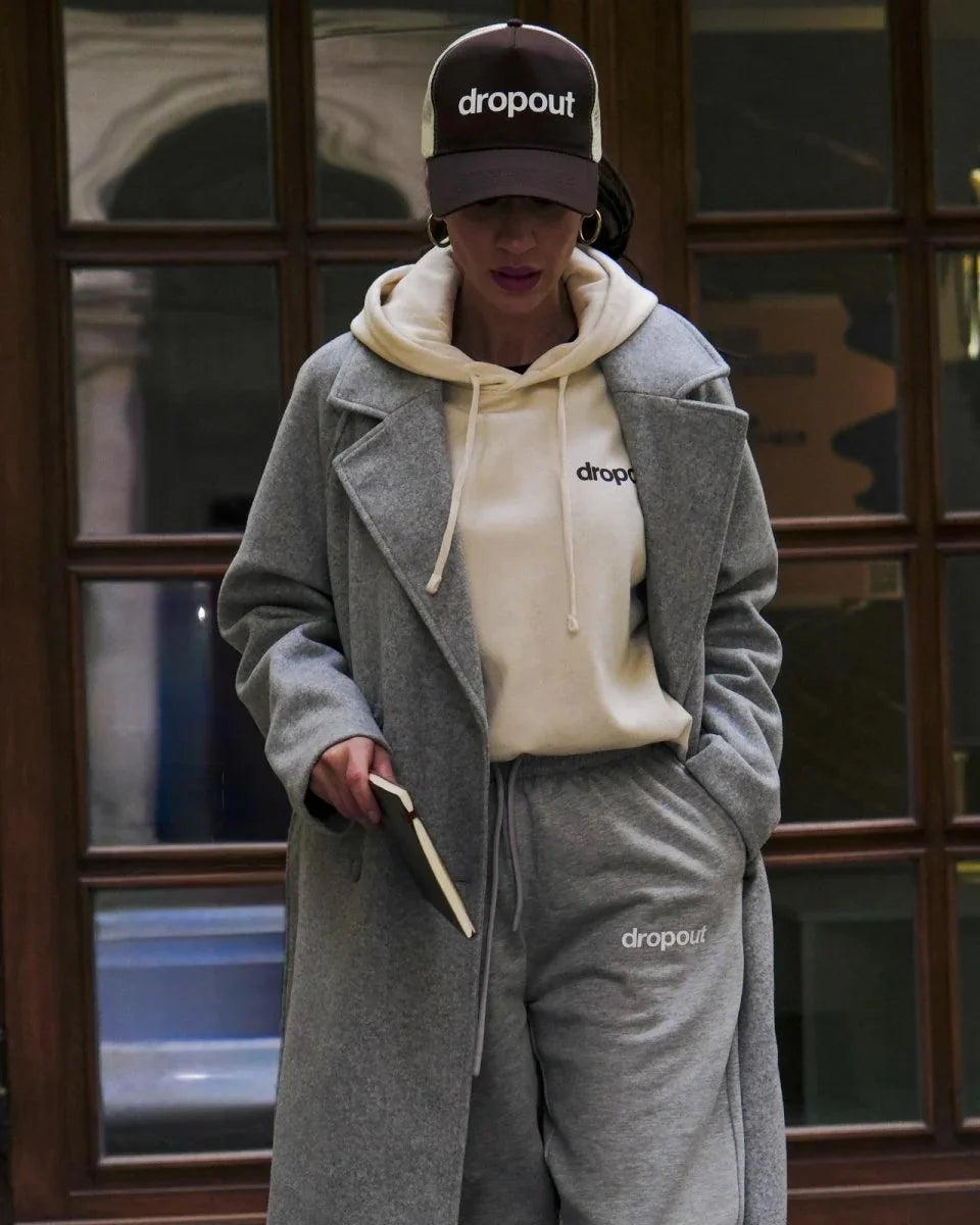 Person wearing a Beige hoodie, and gray pants with 'dropout' branding.
