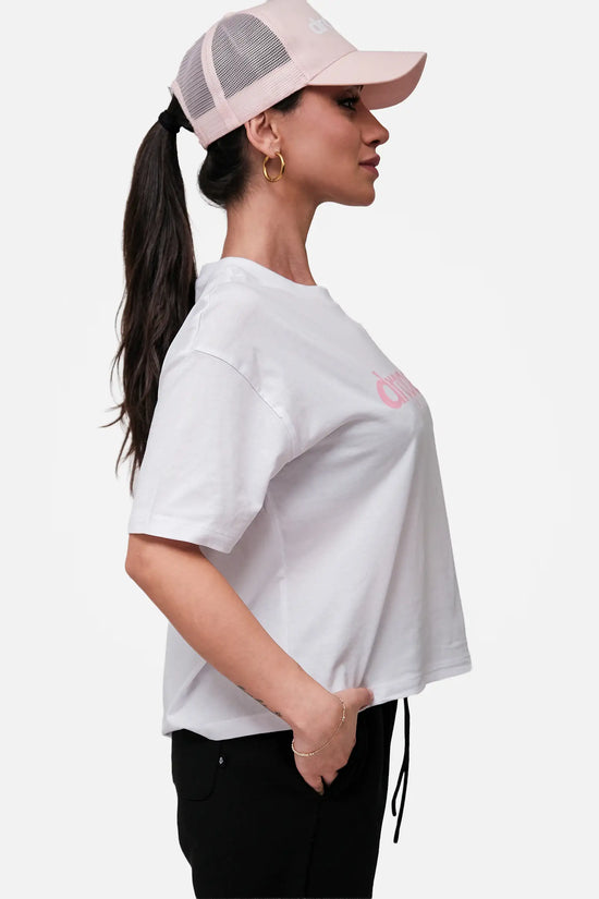 Woman wearing a white t-shirt with a pink logo and a pink cap on a white background