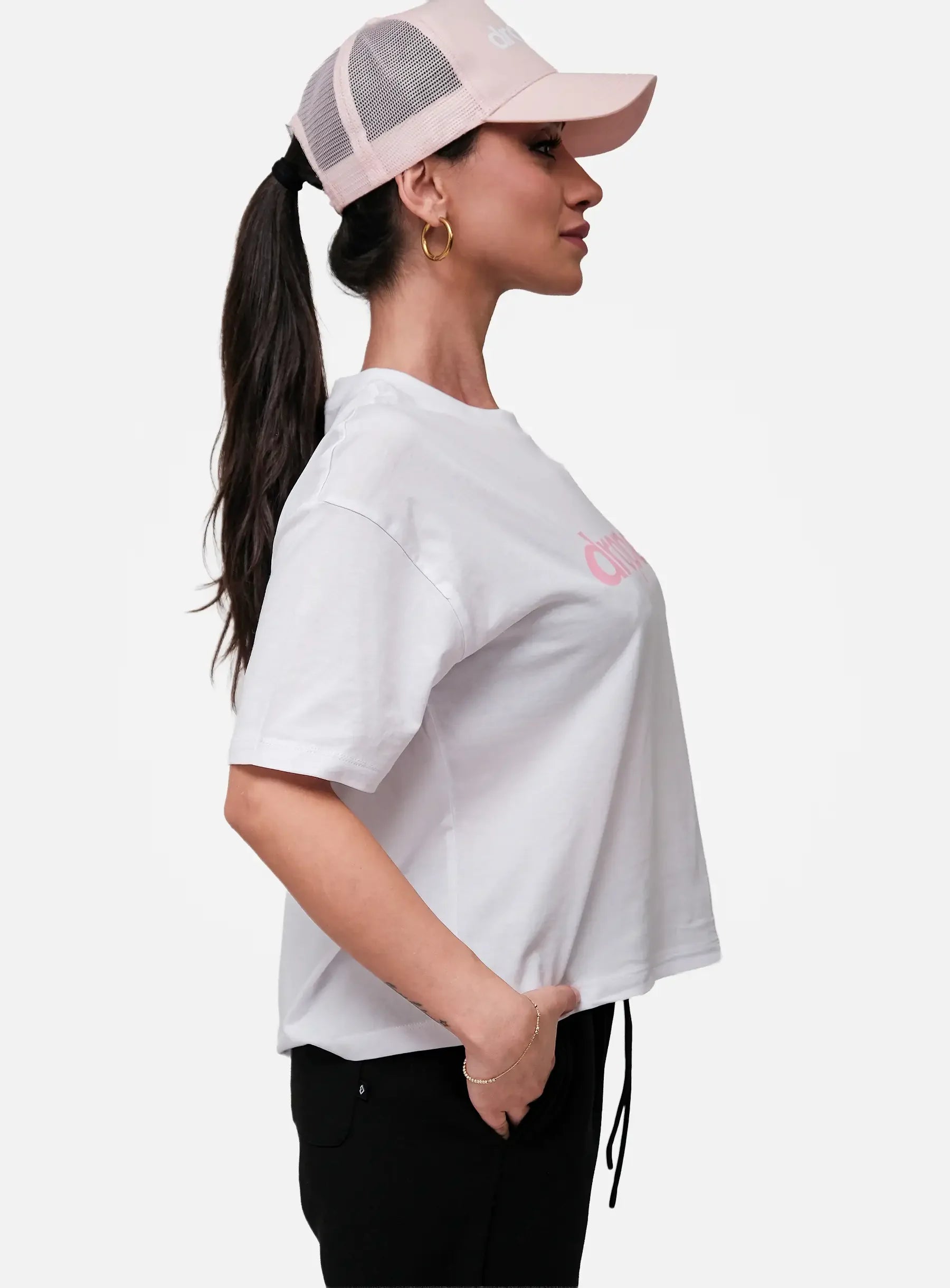 Woman wearing a white t-shirt with a pink logo and a pink cap on a white background