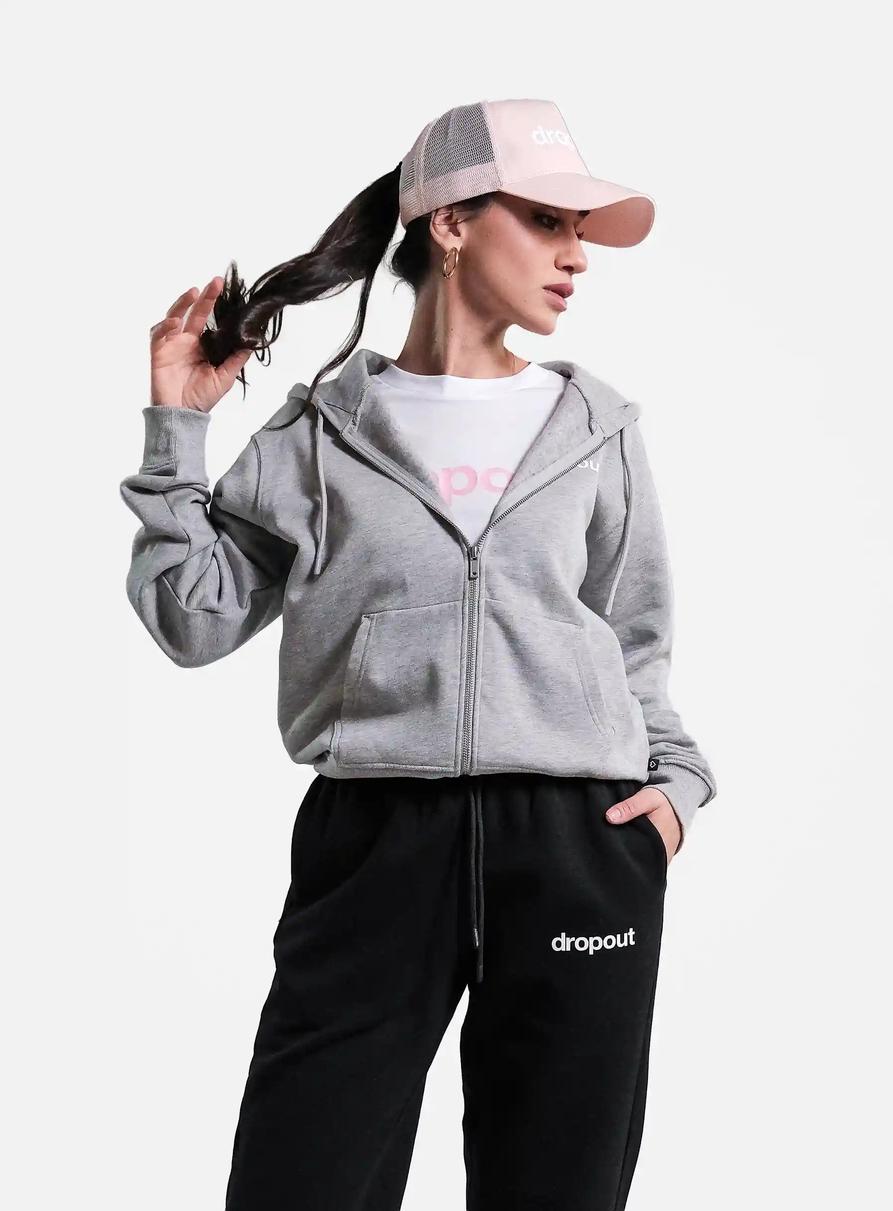 Person wearing a grey hoodie and black pants with 'dropout' branding on a white background