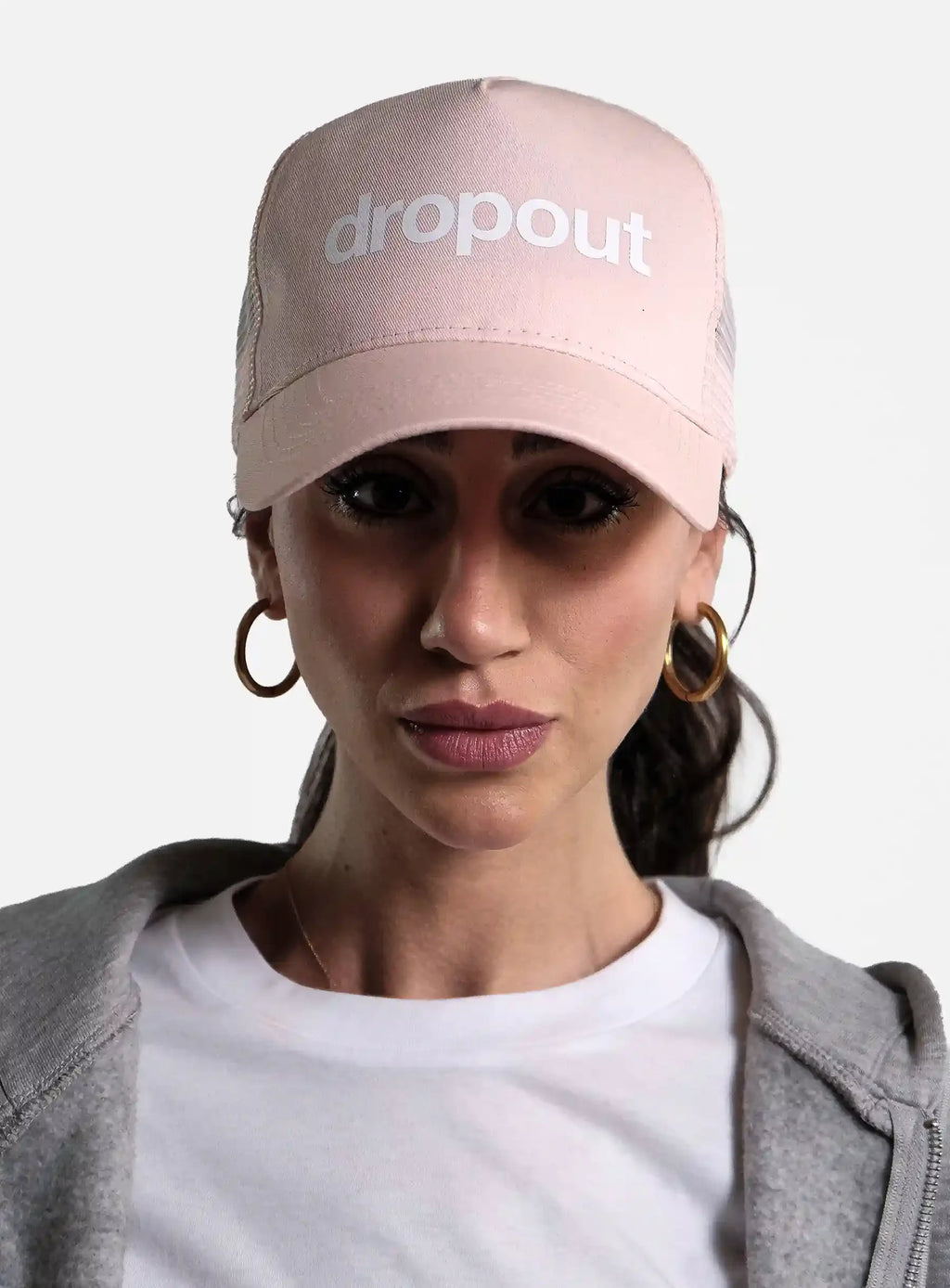 Woman wearing pink dropout cap, white t-shirt, and grey hoodie in streetwear style