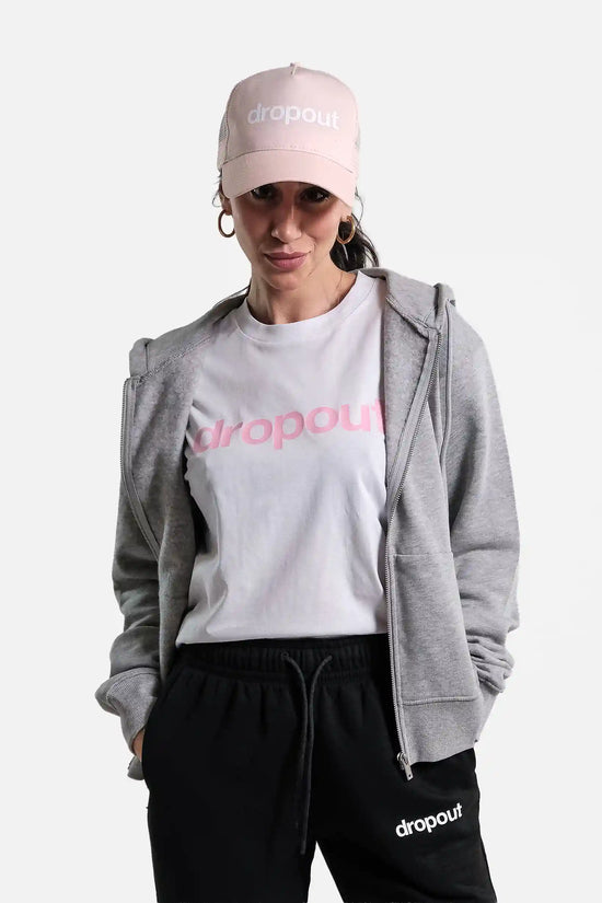 Person wearing a grey hoodie, white t-shirt, black pants, and pink cap with 'dropout' branding on a white background.