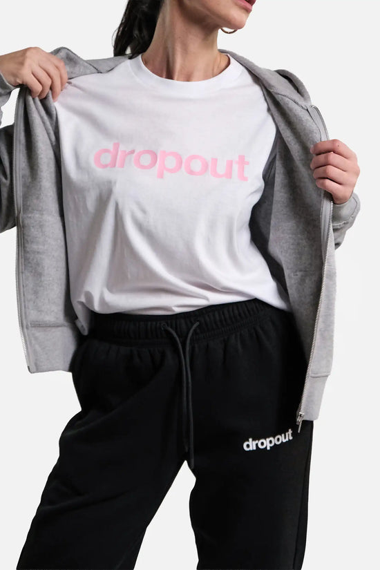 Person wearing a white 'dropout' t-shirt with a grey hoodie and black pants on a light grey background.