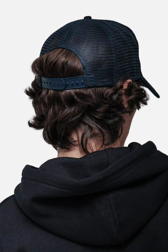Person wearing a black hoodie and White/Navy cap from behind on a white background