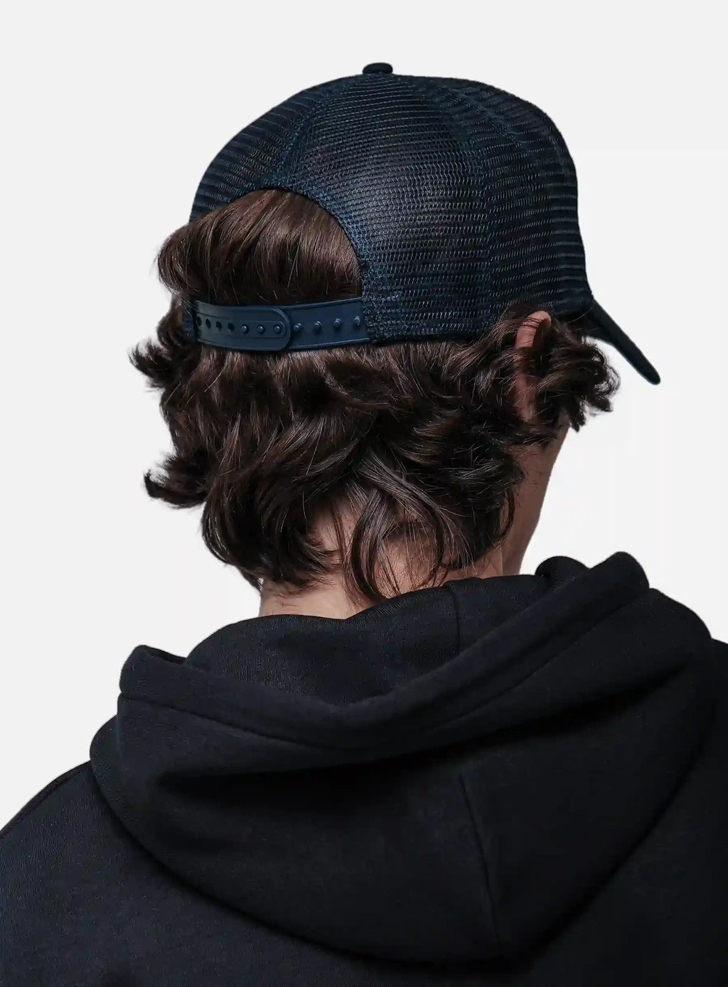 Person wearing a black hoodie and White/Navy cap from behind on a white background