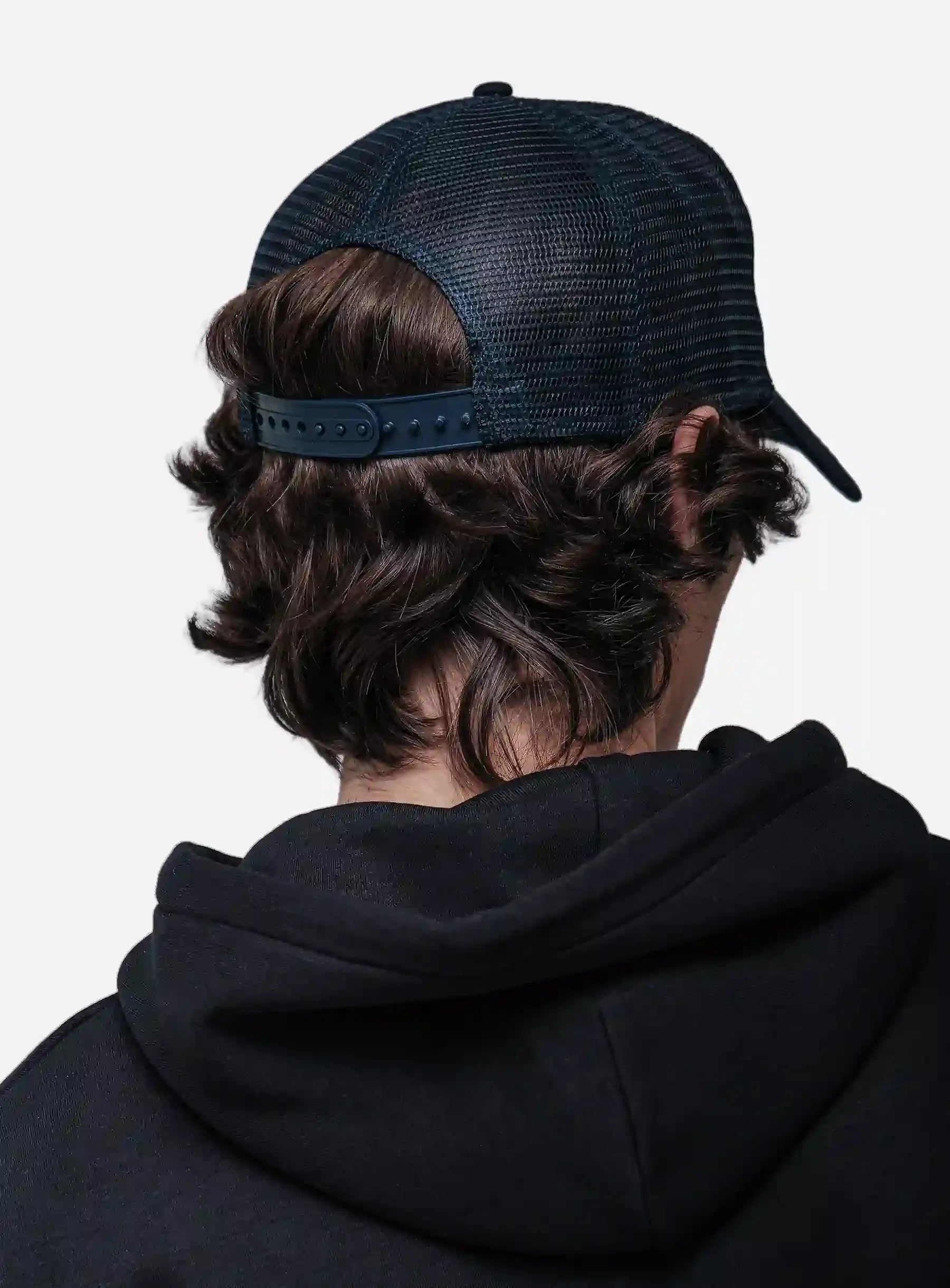 Person wearing a black hoodie and White/Navy cap from behind on a white background