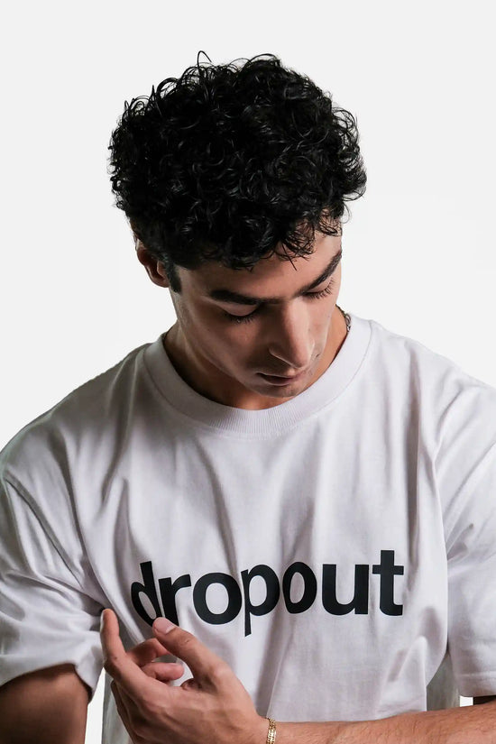 Person wearing a white t-shirt with 'dropout' text on a plain background