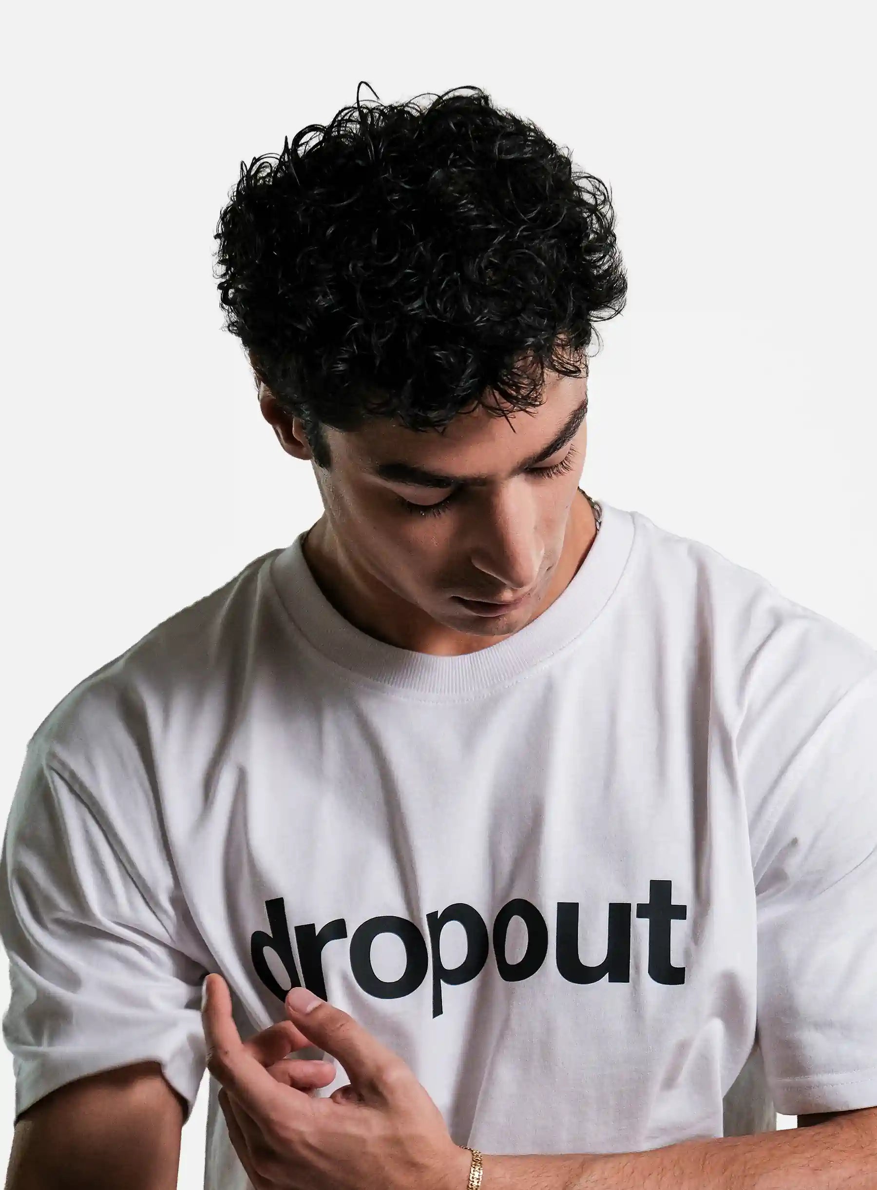 Person wearing a white t-shirt with 'dropout' text on a plain background