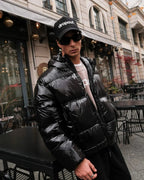 Man wearing dropout Milano black puffer jacket and hat, streetwear style outside café