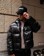 Man wearing dropout Milano black puffer jacket, sweatshirt, and cap, streetwear style